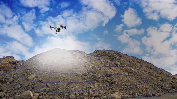 Drone flying above a gravel stockpile with a survey flight path overlaid